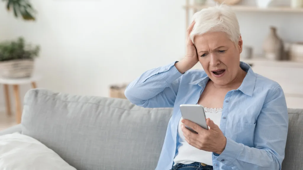 Elderly woman looks at a smartphone in disbelief - Scams